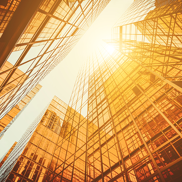 Gold sun shines through glass skyscrapers