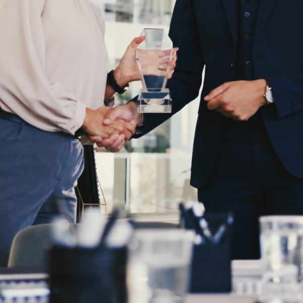 man handing glass award to woman