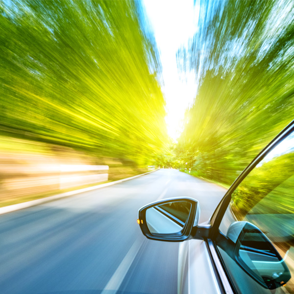 Rear view mirror on car looking into motion with trees