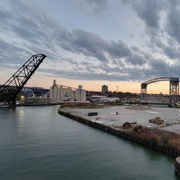 A picture of a port with buildings and bridges at sunset